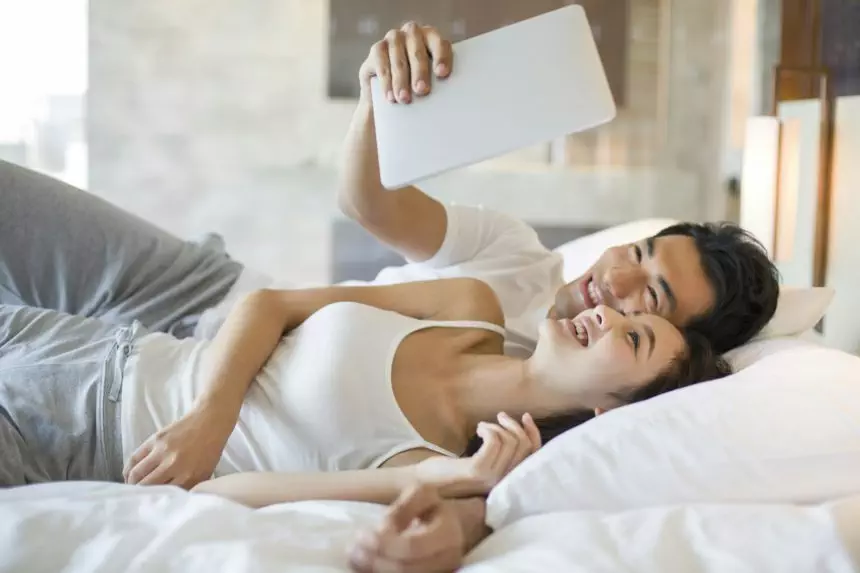 Young couple with digital tablet on bed