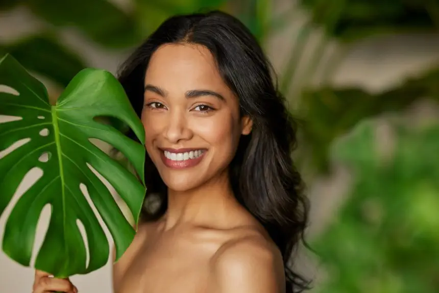 Beauty natural woman with monstera leaf looking at camera