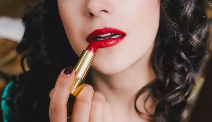 Woman applying red lipstick on lips. Bright makeup for special occasion