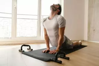 Focused athletic man stretching his body while working out at home