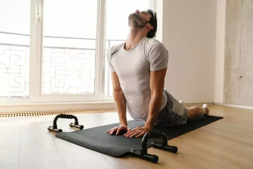 Focused athletic man stretching his body while working out at home