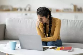 Stressed Young Indian Female Feeling Tired While Study With Laptop At Home