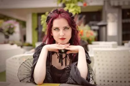 Young gorgeous redheaded woman sitting in an outdoor cafe dressed in retro fashion clothes