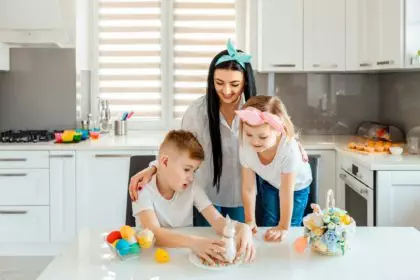 Children with mom make decorations for Easter while sitting at the kitchen table