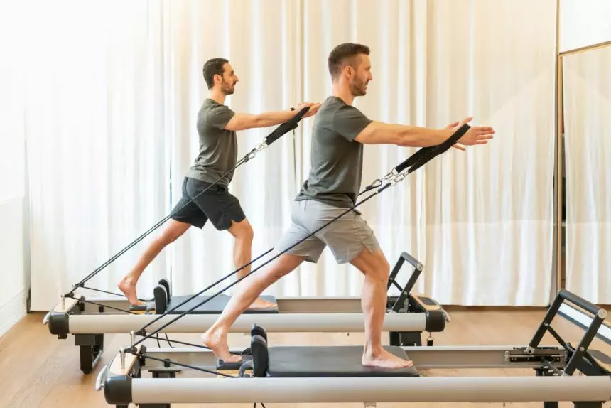 Fit men exercising on pilates machines in gym