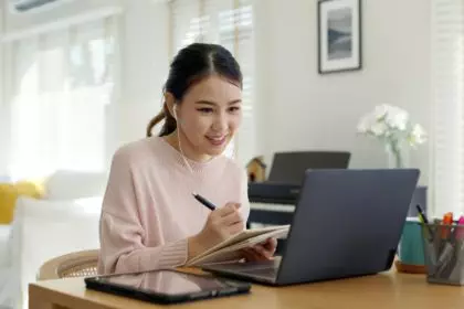 Candid young attractive asian female employee wear earphone listen to digital online