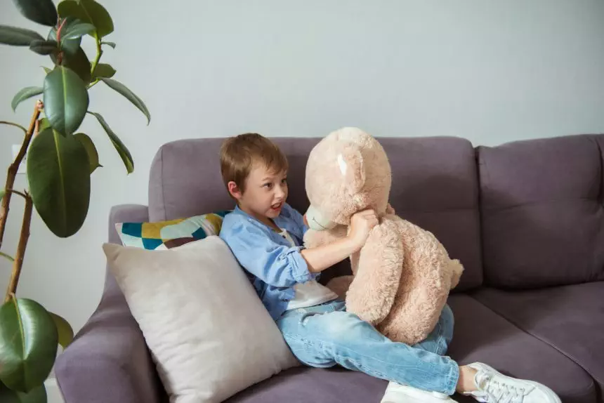 Irritated child boy strangling teddy bear with violence for nervous breakdown or school abuse