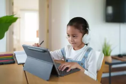 A 6 years old asian little student girl is using tablet for online learning classroom.