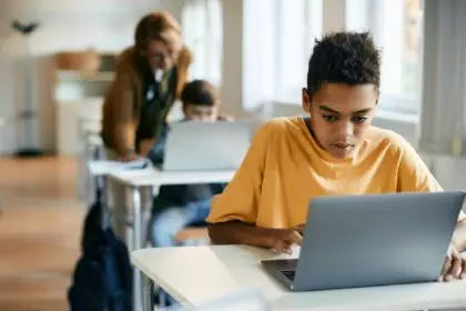Black schoolboy using laptop during computer class at elementary school.