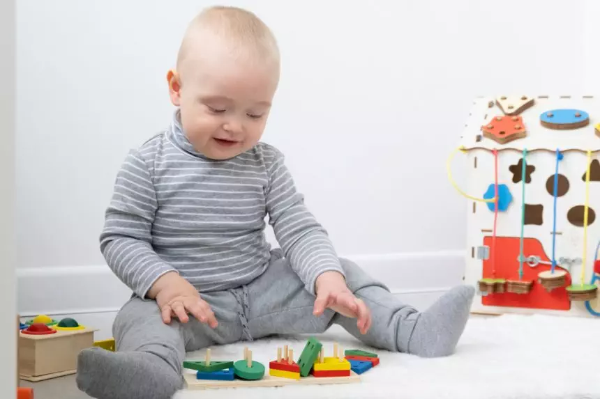 baby boy playing in busy board and wooden toys. early children development