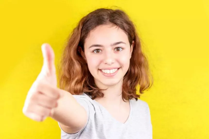 Young teenager girl with thumb up smiling at camera. Positive attitude.