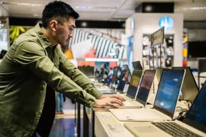 Focused ethnic man choosing laptop in shop