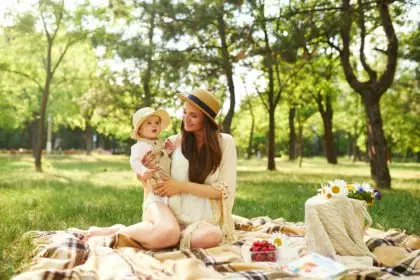 Happy harmonious family outdoors dressed in cool hats. mother with her baby have fan. summer evening
