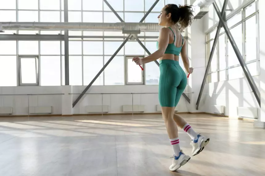 Sporty, beautiful girl performs exercises on jumping rope in gym.Athlete preparing for competition