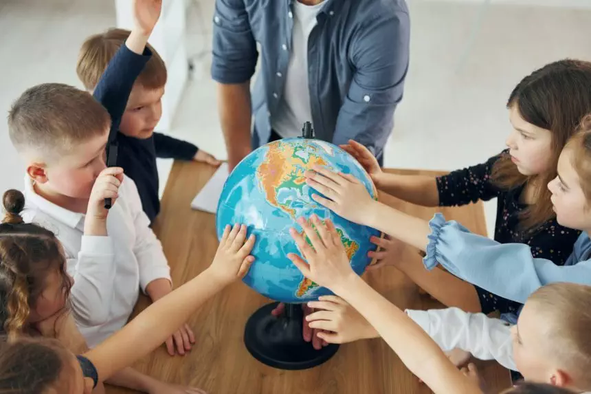 Touching the Earth globe. Group of children students in class at school with teacher