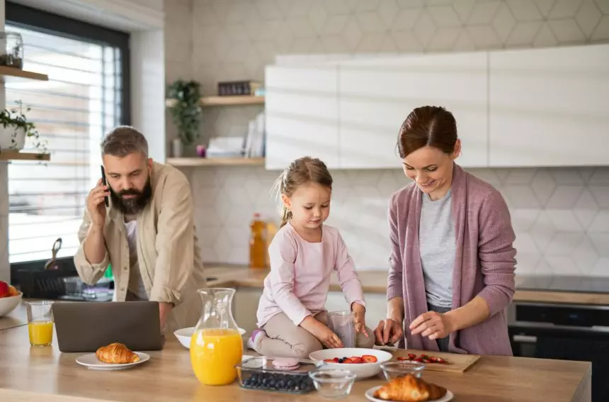 Family with small daughter indoors in kitchen, everyday life and home office with child concept