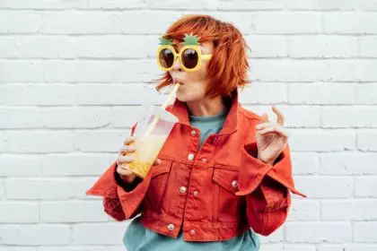 Hipster fashion young woman in bright clothes, funny pineapple glasses drinking tapioca bubble tea