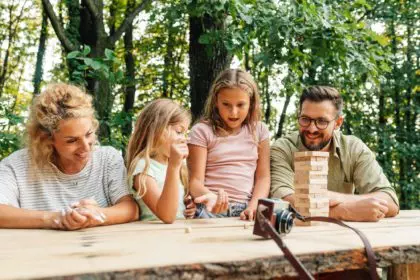 A playful girls playing jenga game with parents in nature.