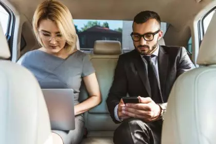 handsome businessman and assistant working in car with laptop and smartphone