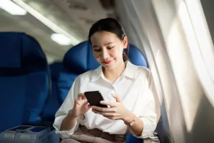 Traveling and technology. Flying at first class. Young business woman passenger using smartphone