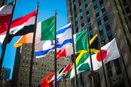 Flags from around the world surrounded by office building and blue sky