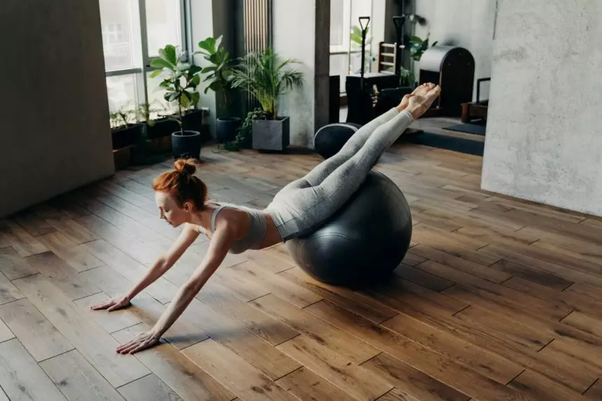 Slim woman balancing on stability exercise ball in fitness studio