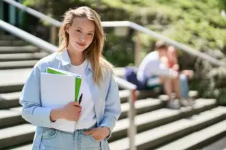 Pretty girl university student holding notebooks posing for outdoor portrait.