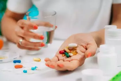 Supplementation. Woman holding a myriad of vitamin and mineral supplements in her hand.